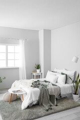 Fototapeta na wymiar Interior of light room with big bed, houseplants and tables