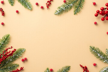Naklejka na ściany i meble Christmas concept. Top view photo of spruce branches in frost and mistletoe berries on isolated beige background with copyspace in the middle