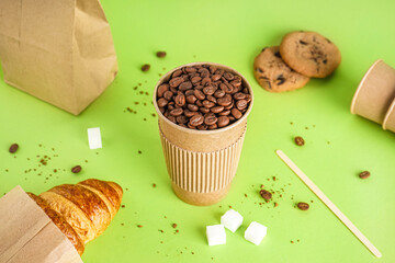 Paper cup of coffee beans on green background - obrazy, fototapety, plakaty