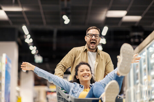 A happy couple having fun with shopping cart in supermarket.