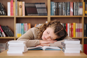 Young women got asleep on the books while studying, reading glasses on head