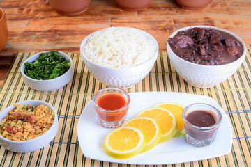 delicious Brazilian feijoada with farofa rice salad served in bowl over piece of wood on blurred background, Brazilian food