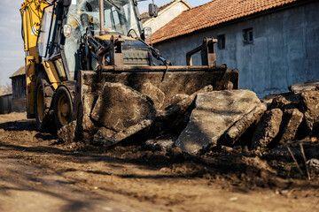 Selective focus on excavator crumbling asphalt.
