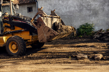 Cropped picture of an excavator lifting soil and asphalt from country road.