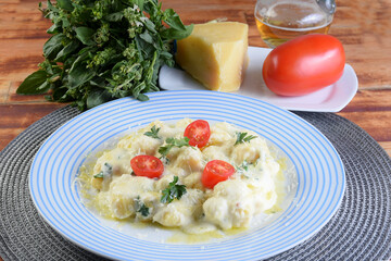 delicious gnocchi pasta in white sauce with parmesan cheese, tomato, basil, herbs, healthy food from Italian and French cuisine