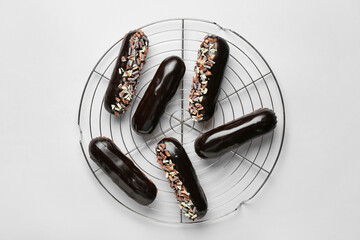 Grid with tasty chocolate eclairs on light background