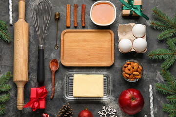 Composition with wooden cutting board, ingredients and utensils for Christmas bakery on dark background