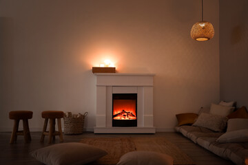 Fototapeta premium Interior of dark living room with fireplace, pillows and burning candles