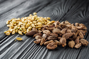 a barrel of dried black cardamom on a black wooden rustic background