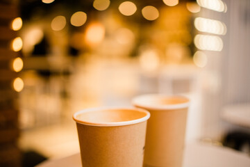 Close up two cardboard coffee cups take away on table over bokeh background copy space and empty space for text - coffee shop and take away drink concept