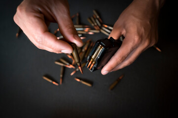 Hands with 5.45 caliber cartridges for weapon closeup.