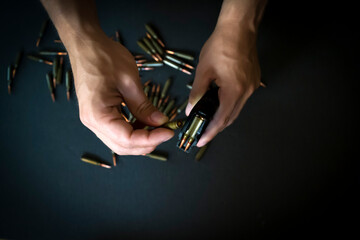 Hands with 5.45 caliber cartridges for weapon closeup.