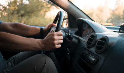 A man is driving a car, hands on the steering wheel closeup.