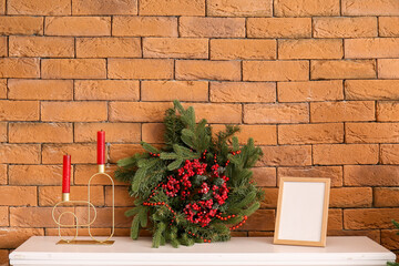 Christmas wreath with frame and candles on mantelpiece near brick wall