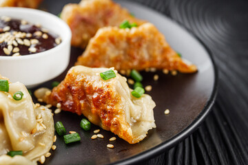 delicious fried gyoza dumplings on a black plate - obrazy, fototapety, plakaty