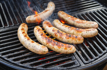 Barbecue Allgäu bratwurst offered as close-up on a charcoal grill with fire and smoke