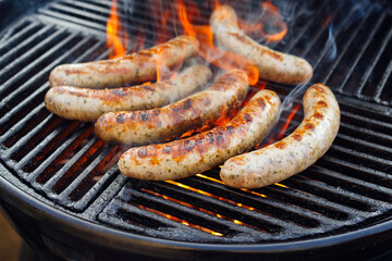 Barbecue Allgäu bratwurst offered as close-up on a charcoal grill with fire and smoke