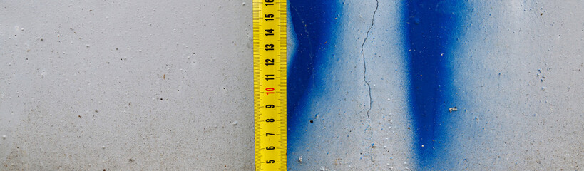 Measuring ruler on a concrete wall texture.