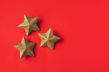 Fototapeta na wymiar Golden sparkling stars on a red background.