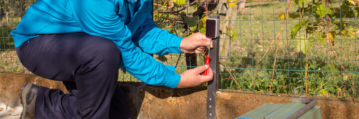 Image of an electrician assembling and repairing the photocell sensor of an automatic gate in a driveway. Handyman at work. Horizontal banner 
