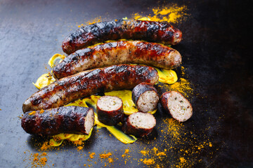 Barbecue Allgäu bratwurst served with hot mustard and curry as close-up on a rustic old board