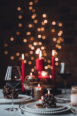 Rustic table decor for Christmas or New Year family dinner. Centrepiece with red candle, dry orange, cone, cinnamon, anise. Zero waste eco-friendly home. Cozy atmosphere, dark background. Close up
