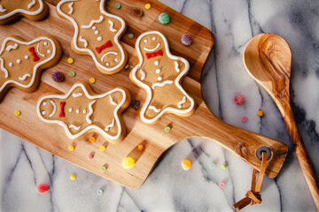 A rustic, festive baking scene with gingerbread men and gumdrops, on a marble worktop background....