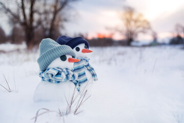 Two little cute snowball snowmen in hats and and striped scarves on the snow on a winter day...