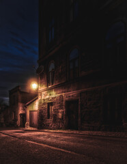 Fototapeta ciemny zaułek uliczki miejskiej w nocy z zamglonym światłem latarni obraz