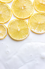 Lemon slices in milk bath closeup. Vertical banner. Natural background for healthy food or skin care products. Selective focus, copy space.
