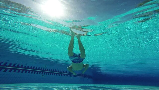 Aquapark. Tourist vacationer male dives underwater in the sun in the swimming pool of water amusement park