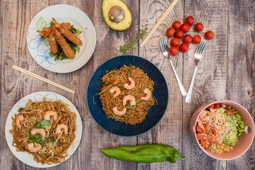 Typical Japanese food recipes with various types of sautéed noodles with seafood, tempura prawns and a poke bowl of salmon and edamame beans