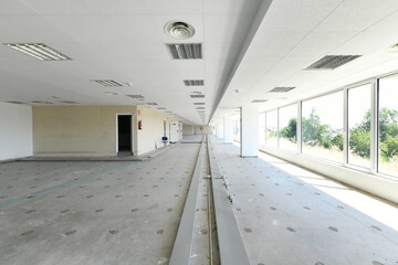 Elongated industrial warehouse offices with technical ceilings and floors with unpaved gutters and a wall of windows with views