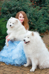redhead (ginger) beautiful young girl in long green dress with three samoyeds outdoor