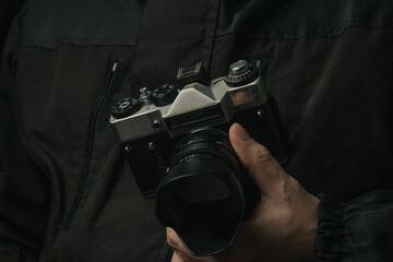 man holding Retro film photo camera isolated on black background soviet