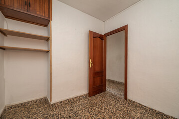 Empty room with dark wood loft furniture, wooden shelves on the wall and grayish terrazzo floors