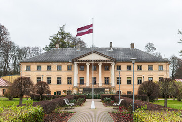 Fototapeta na wymiar Vandzene manor, park and latvian flag on a autumn day, Talsi, Latvia.