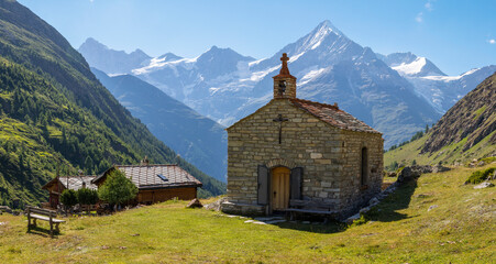 The Walliser alps peaks with the chapel and chalets of Ottafe - Bishorn, Weisshorn, Schalihorn, and Rothorn over the Mattertal valley.