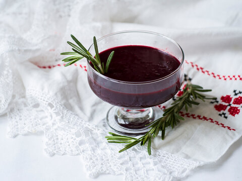 Traditional national belarussian dessert, kulaga, kisel from frozen black currants with rosemary on a white table in glass glasses, horizontal, copy space