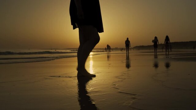 Legs of a woman on the beach at low tide and sunset walks barefoot through romantic places.