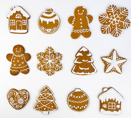 Christmas gingerbread cookies with icing on a white background, in the shape of a house and gingerbread man, Christmas tree and balls, stars and snowflakes and hearts.