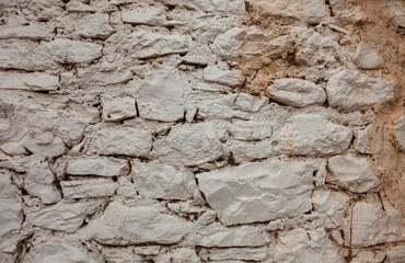 Stonewall of an old village house. White stone wall background.
