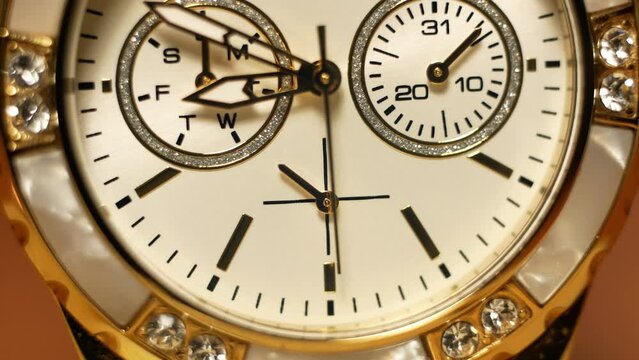 Clock hands in motion on the dial clock face of a gilded gold plated mechanical quartz glamorous chronometer watch close-up macro. Running of time and life