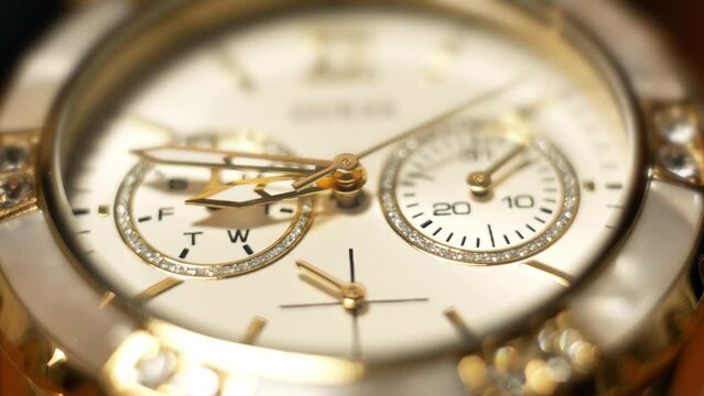 Clock hands in motion on the dial clock face of a gilded gold plated mechanical quartz glamorous chronometer watch close-up macro. Running of time and life 
