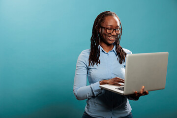 Cheerful happy woman having laptop and smiling heartily while browsing webpages on internet. Joyful...