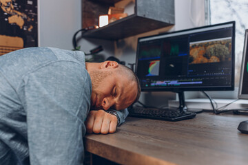 Exhausted businessman sleeping while lying on table during work at home 