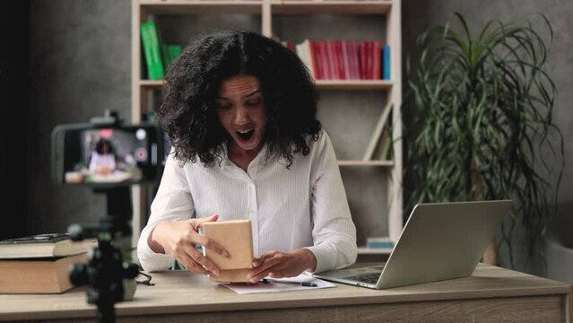 African american woman doing live stream while unpacking box with new smart watch. Female blogger sharing her feedback about modern gadget with her subscribers.