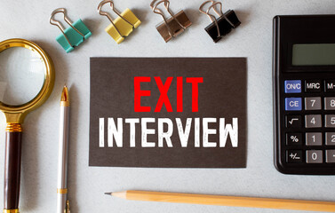 Business concept.Text EXIT INTERVIEW writing on notepaper with pen and magnifying glass on blue...