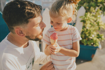 Father and his little daughter eating ice cream and having fun outdoors.