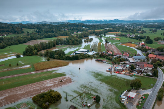 Devastating flood in the valley area, spreading water threatening residential buildings and houses, aerial view.
